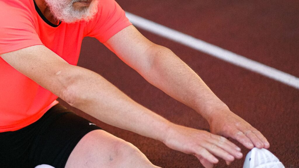 Sportif amateur réalisant des étirements d'échauffement sur une piste d'athlétisme